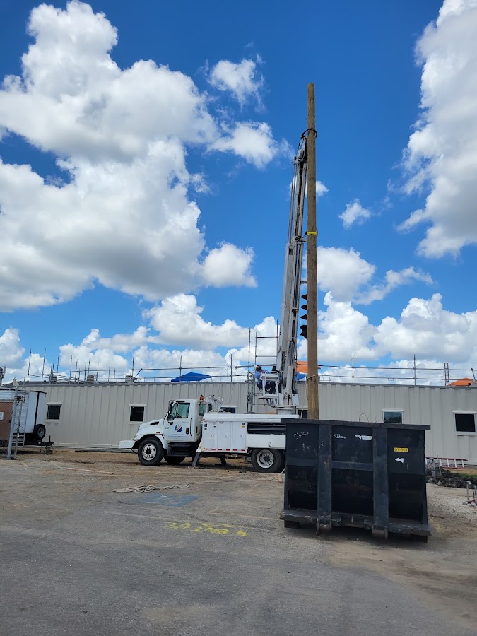 Utility boom truck setting a wooden pole on a Baytown jobsite