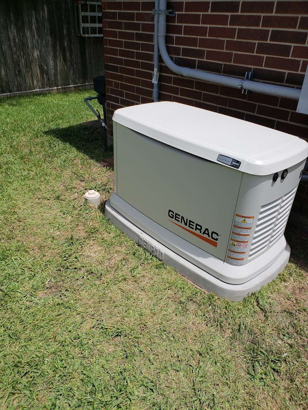 Field photo of a pad-mounted standby generator next to conduit on brick