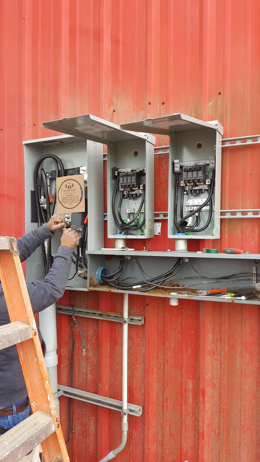 Commercial panel bank with open covers and wireway on industrial siding